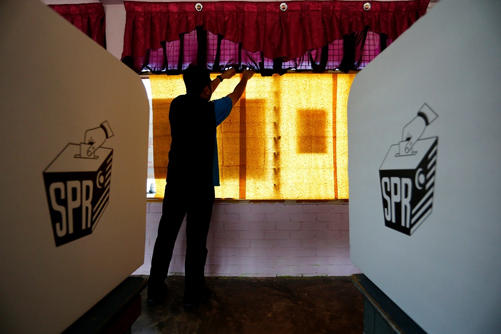 An election volunteer pastes sheets of paper on glass windows a day before the 14th general election at a polling station in Alor Setar May 8, 2018. u00e2u20acu201d Reuters pic