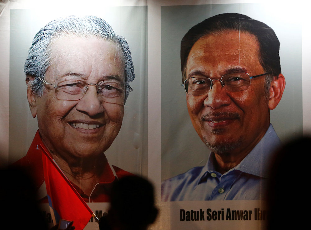 People pass posters of Malaysian Prime Minister Tun Dr Mahathir Mohamad and Datuk Seri Anwar Ibrahim at a rally in Kuala Lumpur May 16, 2018. u00e2u20acu201d Reuters pic