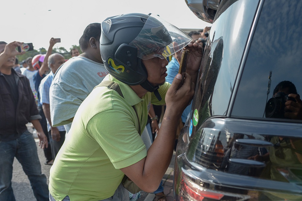 A man uses his phone to take pictures of a vehicle as it enters the Sultan Abdul Aziz Shah Airport in Subang Jaya May 12, 2018.