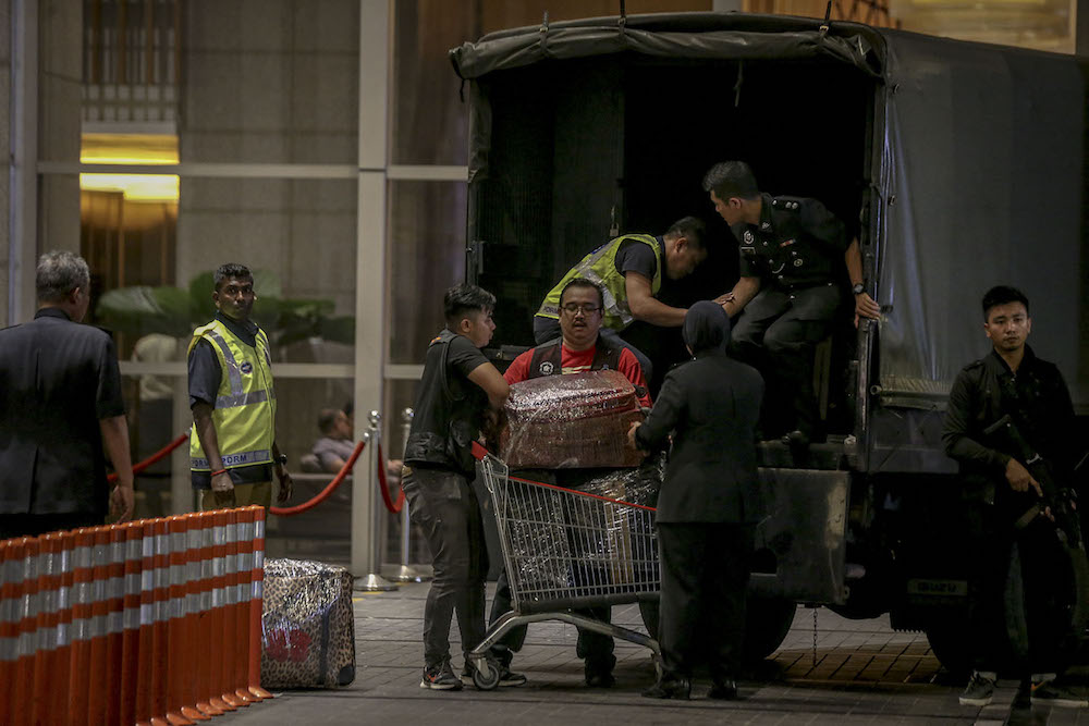 Investigators lift sealed luggage onto a Black Maria outside Pavilion Residences in Kuala Lumpur May 18, 2018. u00e2u20acu201d Picture by Hari Anggara  