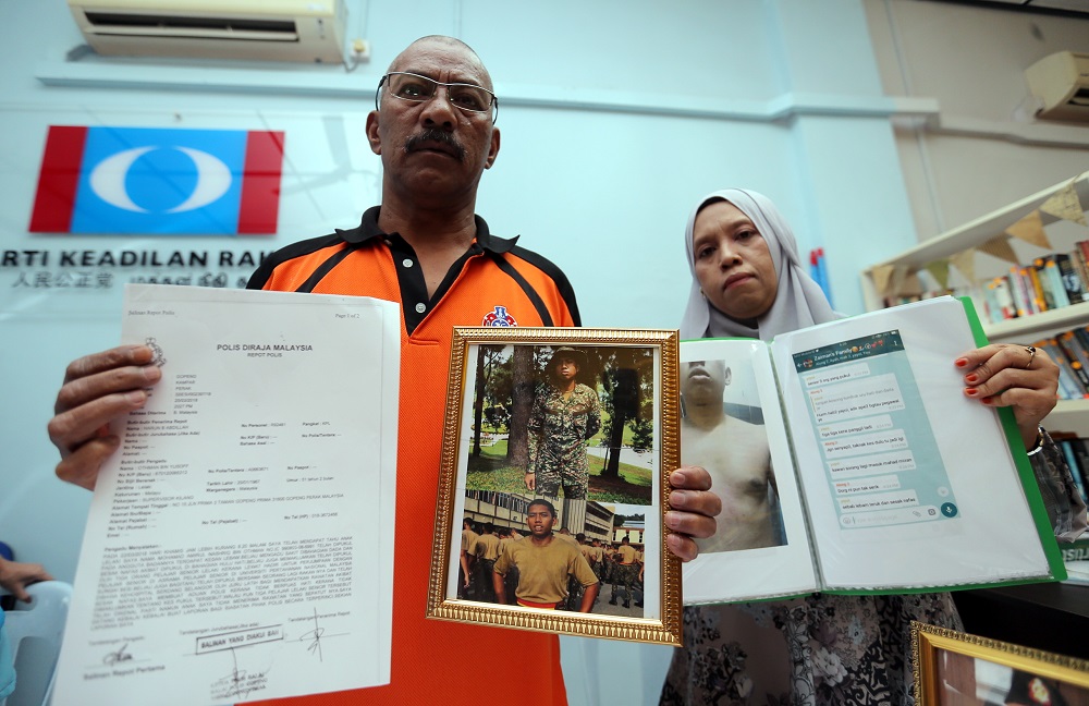 Othman Yusoff (left) shows the police report and pictures of his son, Mohamad Amirul Nashriq Othman, during a press conference in Gopeng May 29, 2018.