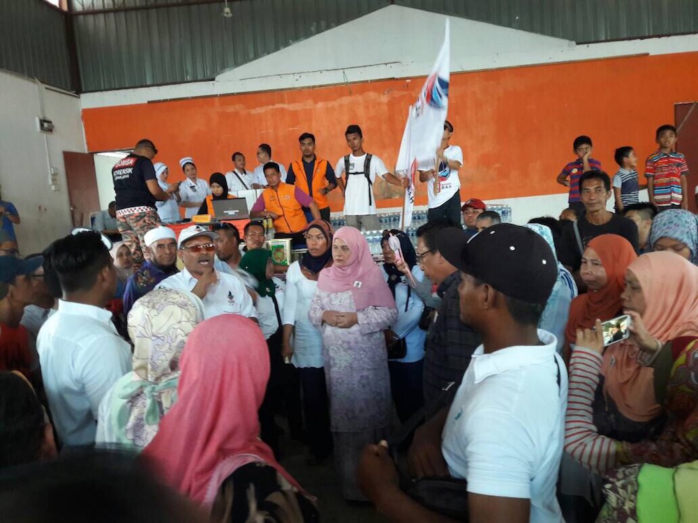 Shuryani listens to a briefing with the residents of Kampung Panji in Semporna who lost their homes and belongings in a fire last night. u00e2u20acu201d Picture courtesy of Parti Warisan Sabah