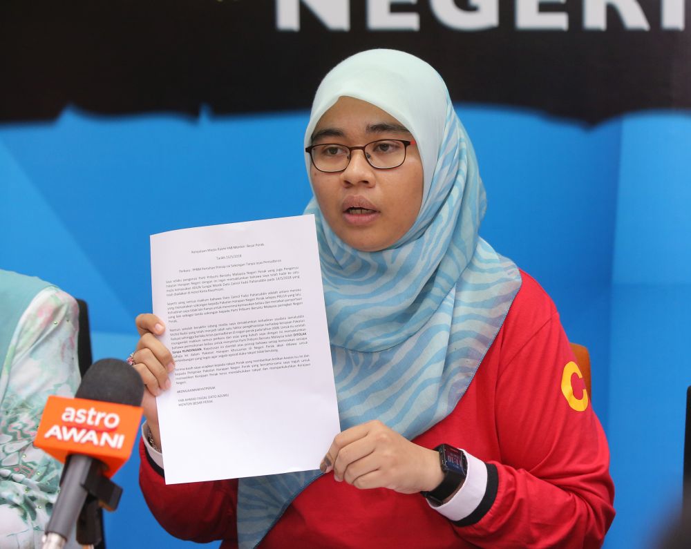PKR information chief Siti Aishah Shaik Ismail (red) shows a statement by Perak PPBM chief Ahmad Faizal Azumu, which announced the rejection of Jamaluddin's application to join the party. u00e2u20acu201d Picture by Marcus Pheong