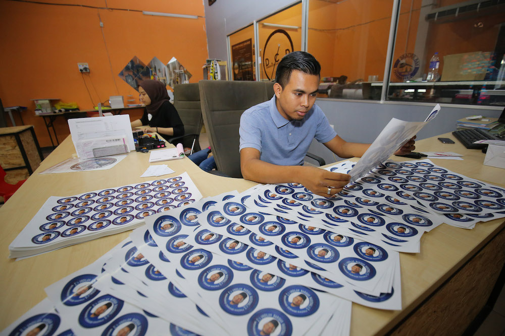 Muhammad Faiz does a final print check of GE14 campaign material. — Picture by Marcus Pheong