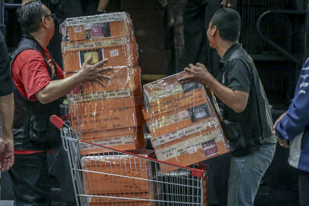 Investigators lift sealed boxes believed to contain luxury designer bags onto a Black Maria outside Pavilion Residences in Kuala Lumpur May 18, 2018. — Picture by Hari Anggara  