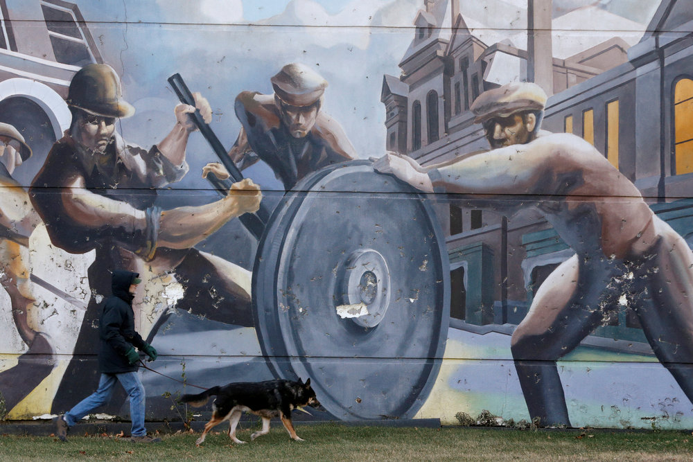 A man walks his dog past a mural depicting factory workers in the historic Pullman neighborhood in Chicago November 20, 2014. u00e2u20acu201d Reuters pic