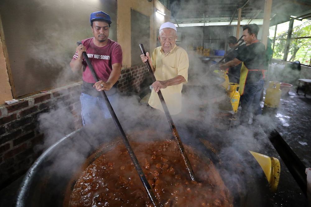 Megat Syahrin Megat Aris and Mohamed Pandak Husien stirring the rendang tok at their shop in Kampung Pasir Putih, Ipoh. u00e2u20acu201d Picture by Farhan Najib