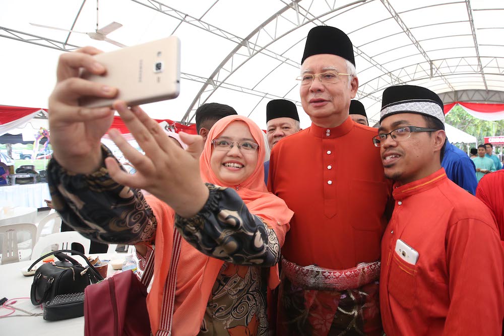 People take selfies with Datuk Seri Najib Razak and Datin Seri Rosmah Mansor at their Aidilfitri open house in Pekan June 15, 2018. — Picture by Azinuddin Ghazali