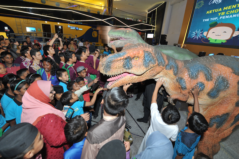 Children touch a replica dinosaur at The Top in George Town June 1, 2018. — Picture by KE Ooi