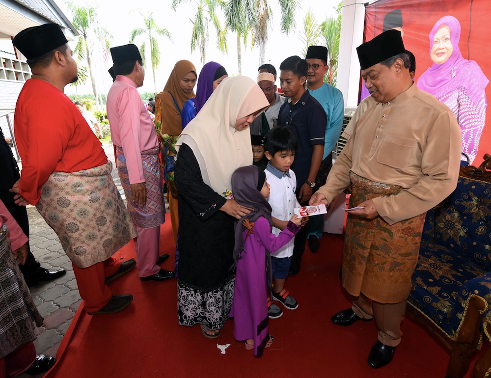 Home Minister Tan Sri Muhyiddin Yassin gives ‘duit raya’ to children at the Pagoh parliamentary constituency Aildifitri open house in Pagoh June 17, 2018. — Bernama pic