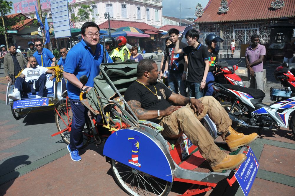 Low (centre) pedals a trishaw carrying US rapper Busta Rhymes in George Town on April 19, 2013. u00e2u20acu201d Picture by KE Ooi