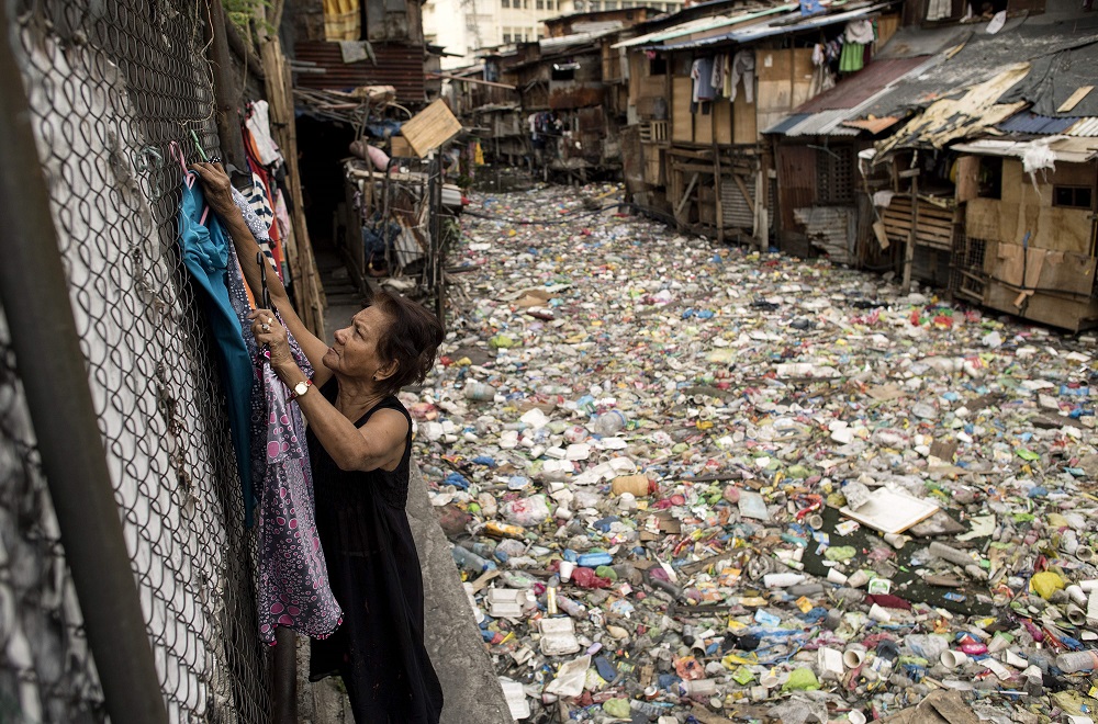 This photo taken on May 12, 2018 shows Perigrina Santos, 81, collecting her laundry next to a garbage-filled creek in Manila. u00e2u20acu201d AFP pic