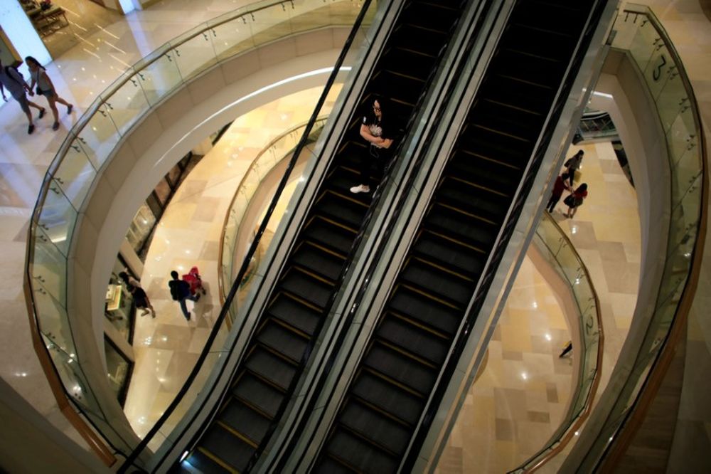 A woman rides down an escalator at a shopping mall in Singapore June 17, 2017. u00e2u20acu201d Reuters pic