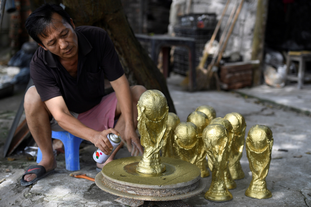 Vietnamese craftsman Vuong Hong Nhat spraying gold colour paint on a plaster model of the football World Cup trophy at a workshop in Hanoi. u00e2u20acu201d AFP pic