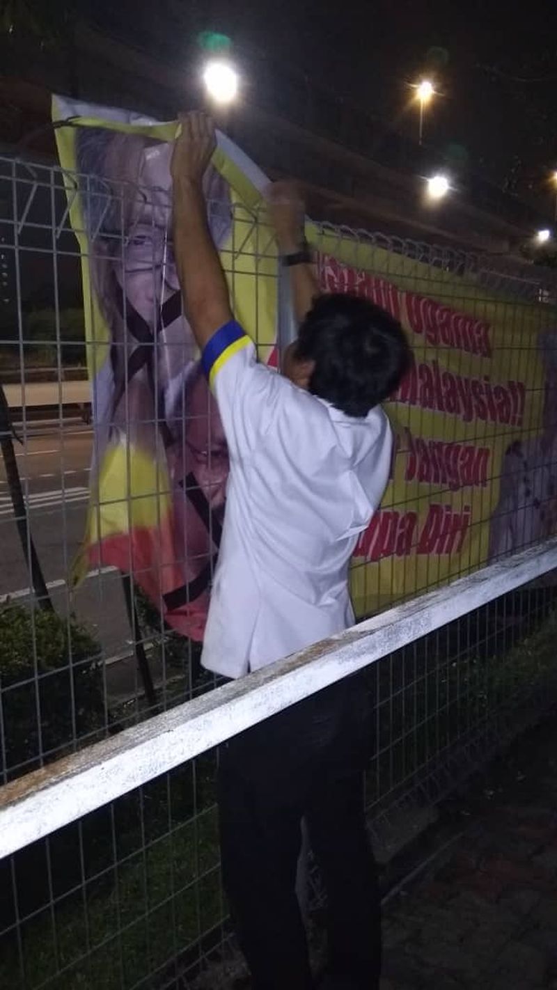 A man is seen removing the provocative banner from the KTM station area, June 8, 2018. u00e2u20acu2022 Picture courtesy of KTMB