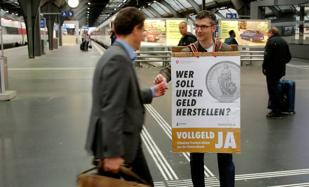 A member of the sovereign money initiative, a referendum campaign that would abolish traditional bank lending, offers flyers to travellers at the central railway station in Zurich May 3, 2018. u00e2u20acu201d Reuters pic