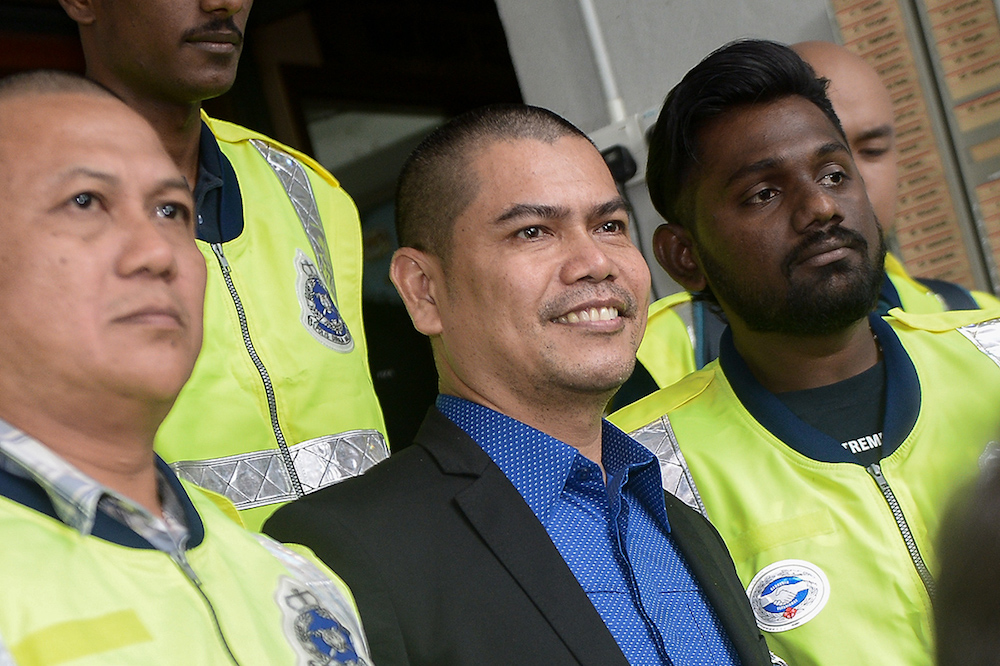 Datuk Seri Jamal Yunos smiles for the press as he is escorted out by police outside the Shah Alam Court, July 11 2018. u00e2u20acu201d Picture by Mukhriz Hazim