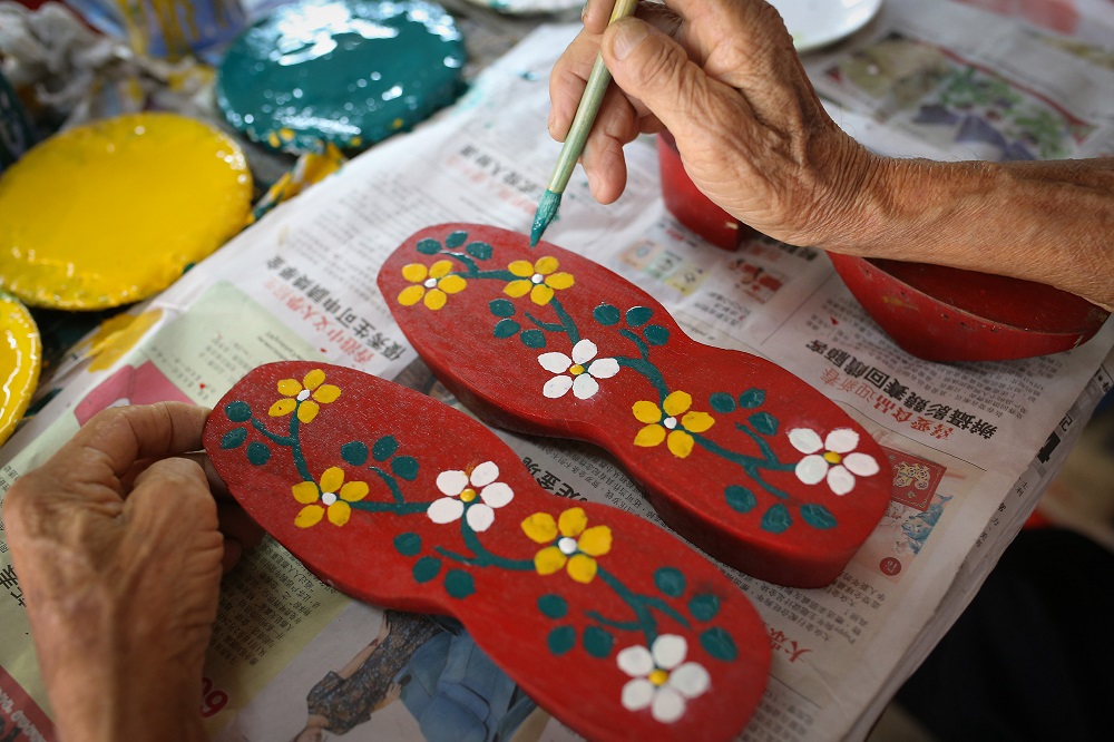 Cheah Bak Chong skilfully paints a pair of wedding clogs at his shop in Jalan Silang, Ipoh.
