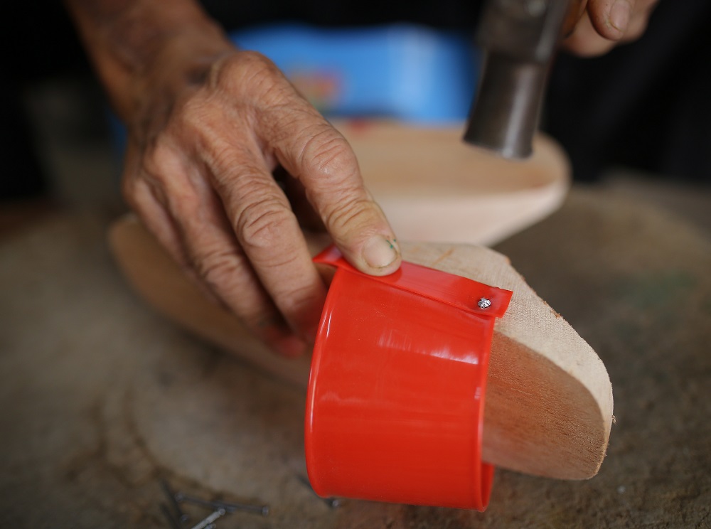 Cheah Bak Chong hammering the plastic straps on the wooden shoe at his shop in Jalan Silang, Ipoh.