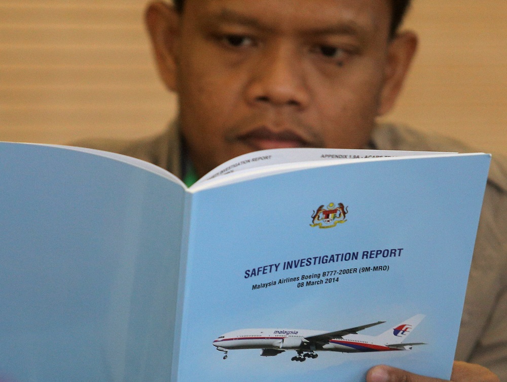 A family member reads an MH370 briefing report before a closed door meeting in Putrajaya July 30, 2018. u00e2u20acu201d Reuters pic
