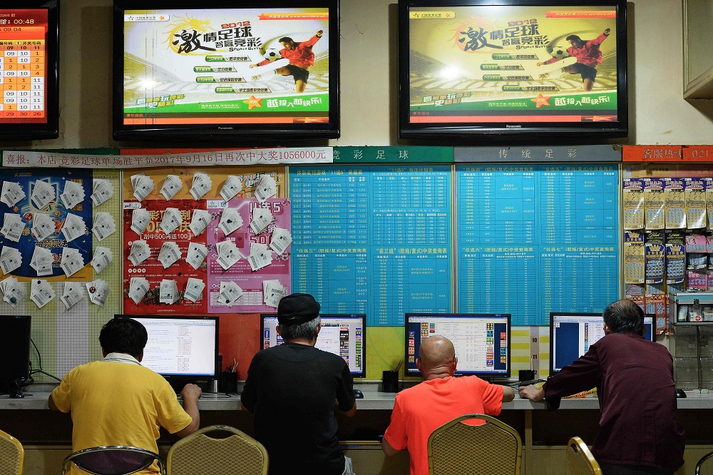 This photo taken on July 2, 2018 shows people checking information of the 2018 Russia World Cup tournaments at a China Sports Lottery outlet in Shanghai. u00e2u20acu201d AFP pic