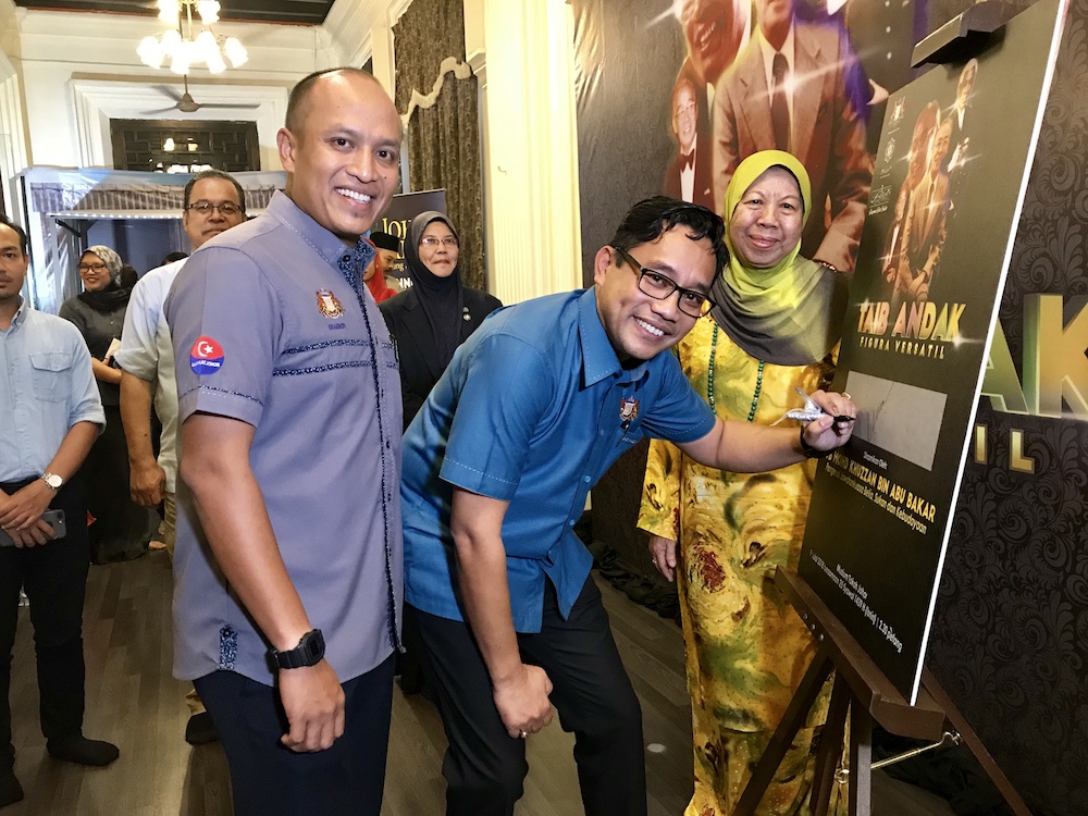 Johor Youth, Sports, Culture and Heritage Committee chairman Mohd Khuzzan Abu Bakar (centre) signing the u00e2u20acu02dcTaib Andak Figura Vesatilu00e2u20acu2122 exhibition poster at the Muzium Tokoh Johor in Johor Baru. u00e2u20acu201d Picture by Ben Tan