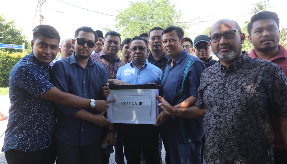 Ghulam Muzaffar Gulam Mustakim holds up a box with the words u00e2u20acu02dcFree Najibu00e2u20acu2122 for the launch of a donation drive for the embattled former prime minister. u00e2u20acu201d Picture from China Press
