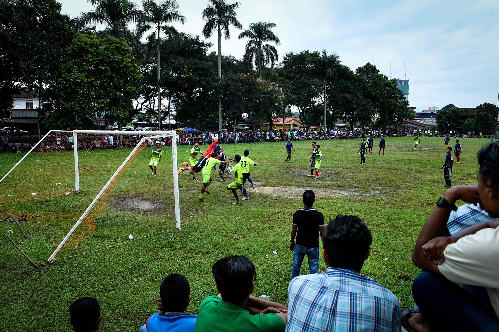 This picture taken on June 17, 2018 shows Rohingya residents watching Rohingya FC and Cheras Harimau teams play during a three-day tournament for refugees on the outskirts of Kuala Lumpur. u00e2u20acu201d AFP pic