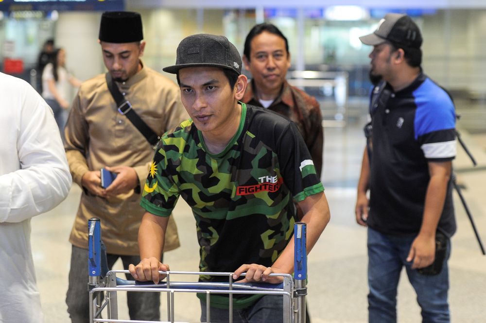 Hafiz (centre) arrives at KLIA from Indonesia to collect the remains of his late wife on July 31, 2018. u00e2u20acu2022 Picture by Shafwan Zaidon