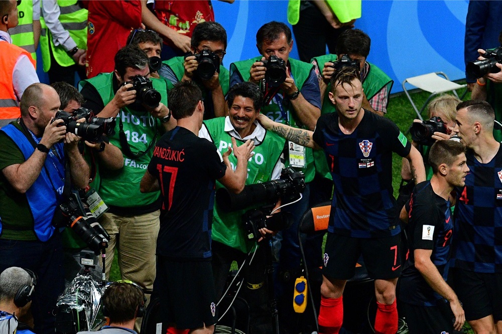 Mario Mandzukic (left) shakes hands with AFP photographer Yuri Cortez (centre) after falling on him with teammates while celebrating their second goal during the World Cup semi-final match at the Luzhniki Stadium in Moscow on July 11, 2018. u00e2u20acu201d AFP pic