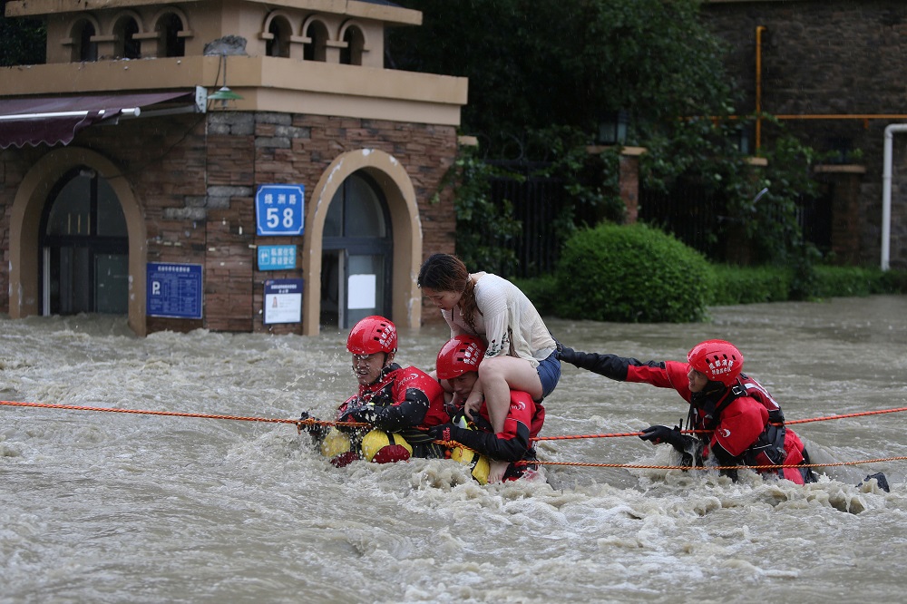 Firefighters rescue a stranded woman on a flooded street, following heavy rainfall in Chengdu, Sichuan province, China July 11, 2018. u00e2u20acu201d Picture by Wang Hongqiang/Chengdu Economic Daily via Reuters