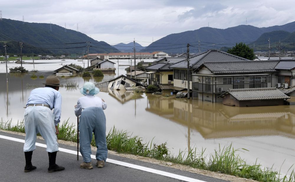 An elderly couple looks at a flooded area after heavy rain in Kurashiki, Okayama Prefecture, Japan, in this photo taken by Kyodo. u00e2u20acu201d Reuters pic