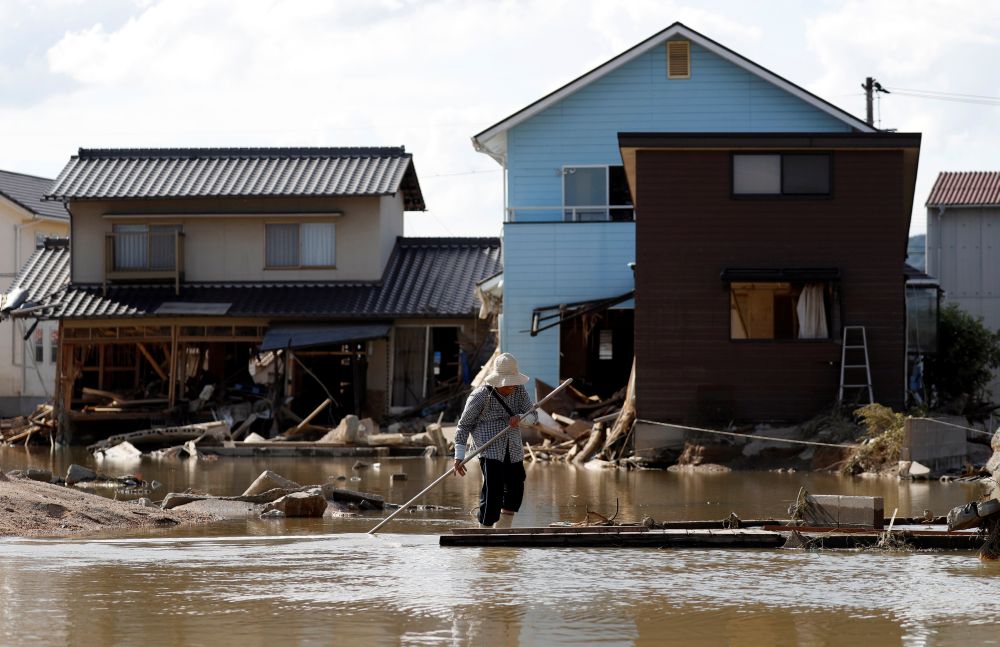 An elderly woman walks next to submerged and destroyed houses in a flooded area in Mabi town in Kurashiki, Okayama Prefecture July 9, 2018. u00e2u20acu201d Reuters pic