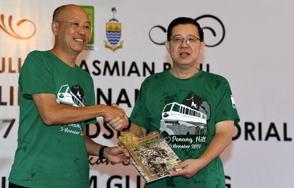 Finance Minister Lim Guan Eng (right) receiving the book entitled u00e2u20acu02dcHealing Penang Hillu00e2u20acu2122 from Penang Hill Corporationu00e2u20acu2122s Cheok Lay Leng at Penang Hill today, July 28, 2018. u00e2u20acu2022 Bernama pic