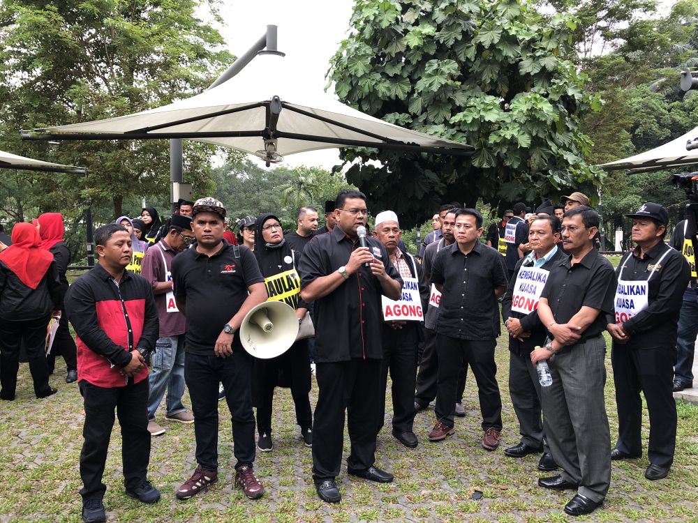 The group, complete with placards, listen to a briefing being given by Lokman as they await for more supporters. 