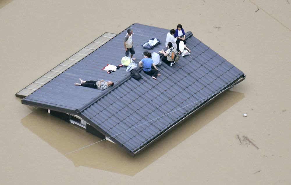 An aerial view shows local residents seen on the roof of submerged house at a flooded area as they wait for a rescue in Kurashiki, southern Japan, July 7, 2018. u00e2u20acu201d Kyodo picture via Reuters