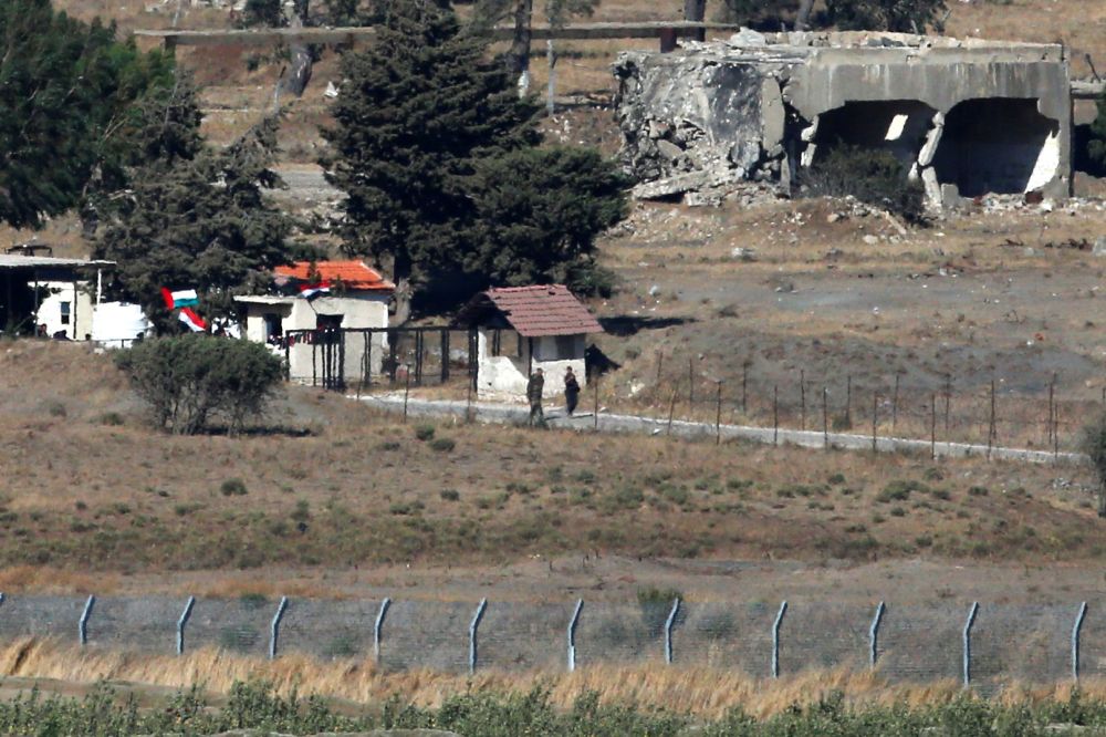 Uniformed men walk near a building with Syrian and Ba'ath Party flags in Quneitra, on the Syrian side of the ceasefire line between Israel and Syria, as seen from the Israeli-occupied Golan Heights. u00e2u20acu201d Reuters pic
