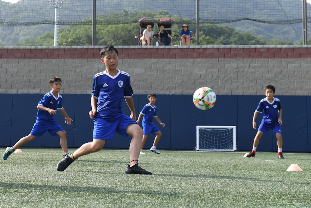Young South Korean football students play on the pitch as their parents (top) look on at SON Football Academy in Chuncheon July 28, 2018. — AFP pic