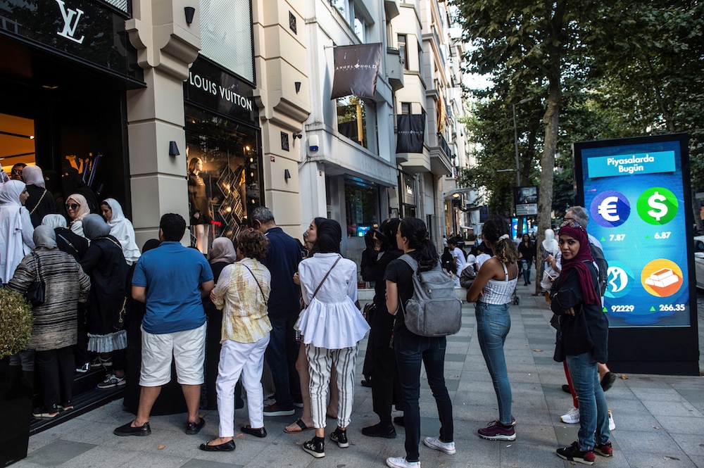 Tourists, many from Saudi Arabia and Asia, queue outside a luxury brand Louis Vuitton store next to a billboard giving currencies rates in Istanbul August 13, 2018. u00e2u20acu201d AFP pic