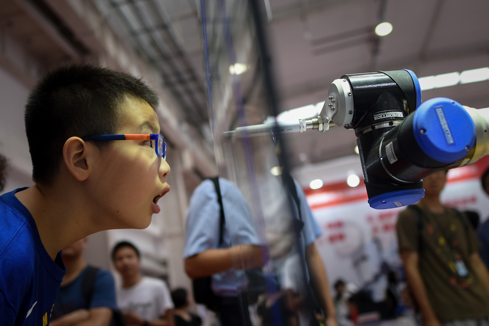 A boy looks at a robot arm at the 2018 World Robot Conference in Beijing August 15, 2018. u00e2u20acu201d AFP pic