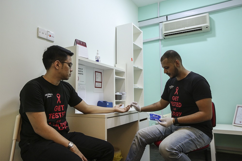 CHCC coordinator Zain Ghassan (right) with administrative staff member Hakim Redza demonstrate how a HIV test is done.