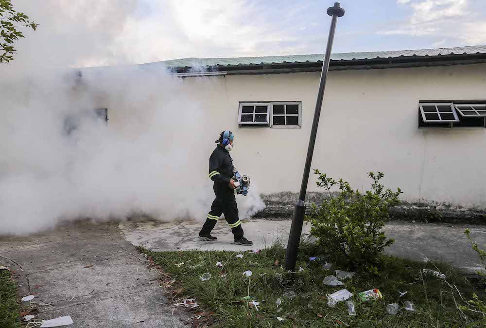 A municipal council worker carries out fogging on the grounds of an apartment block in Petaling Jaya August 23, 2018. u00e2u20acu201d Picture by Firdaus Latif
