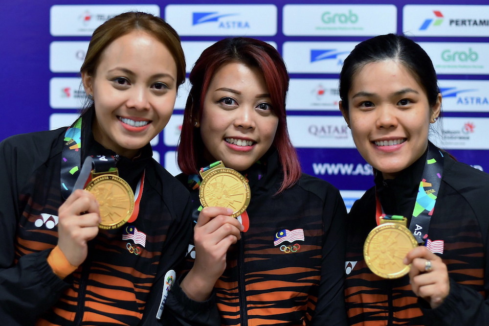 Syaidatul Afifah Badrul Hamidi, Siti Safiyah Amirah Abdul Rahman dan Esther Cheah Mei Lan bangga menunjukkan pingat emas pertama Malaysia dari skuad boling pada temasya Sukan Asia ke-18 di Komplex Sukan Boling Jakabaring, 22 Ogos 2018. u00e2u20acu201d Foto Bernama