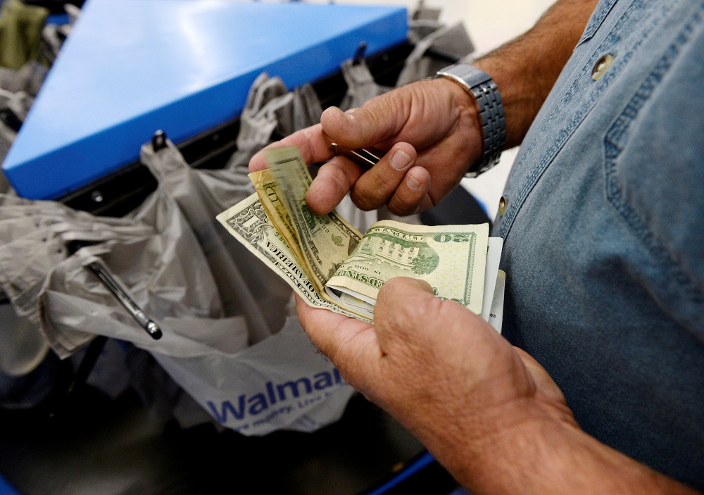 A customer counts his cash at the checkout lane of a Walmart store in the Porter Ranch section of Los Angeles, California, November 26, 2013. u00e2u20acu201d Reuters pic