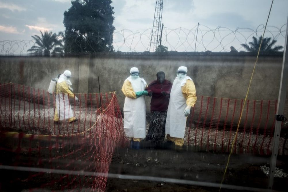 An Ebola patient is lead by two medical workers into a Biosecure Emergency care Unite (CUBE) on August 15, 2018 in Beni. The new ETC will hold ten CUBEs, which will be used for the first time to treat Ebola patients. u00e2u20acu201d AFP pic