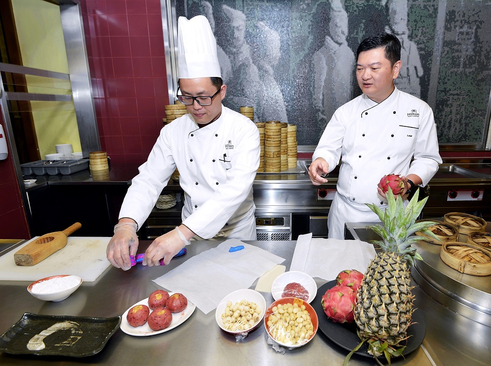 Lam (right) and a chef from Chynna demonstrate how to make the signature Dragon Blossom mooncake featuring dragon fruit and pineapple flavours. — Picture by Ham Abu Bakar
