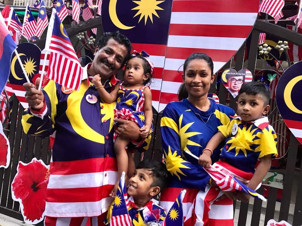 Businessman M. Kandapan with his grandchildren and daughter K. Larvaniaa outside their Merdeka-themed home in Bandar Seri Alam in Masai. — Picture by Ben Tan