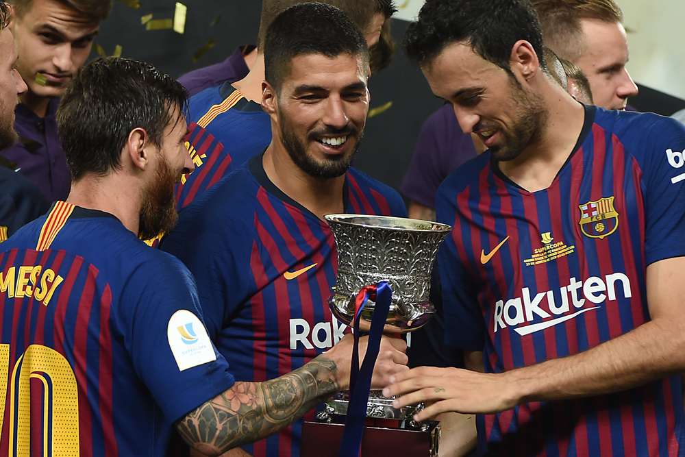 Barcelona's Lionel Messi (left) presents the cup to Sergio Busquets (right) next to Luis Suarez as they celebrate winning Spanish Super Cup final with Sevilla in Tangiers August 12, 2018. u00e2u20acu201d AFP pic