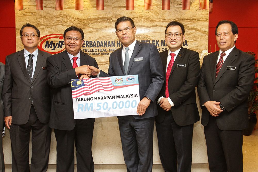 Saifuddin (centre) poses with the mock cheque from MyIPO. u00e2u20acu201d Picture by Miera Zulyana
