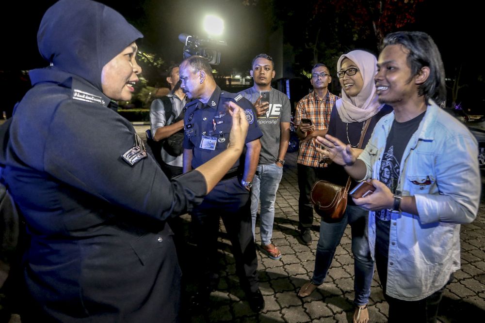 Forum organisers speak to the auxiliary police after they were told to halt proceedings. — Picture by Hari Anggara